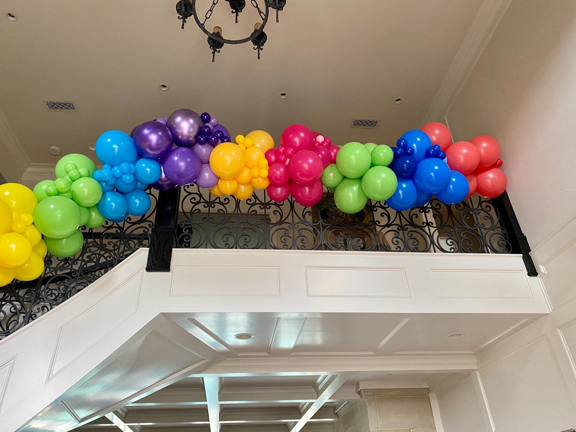 A bunch of colorful balloons are hanging from the ceiling of a room.