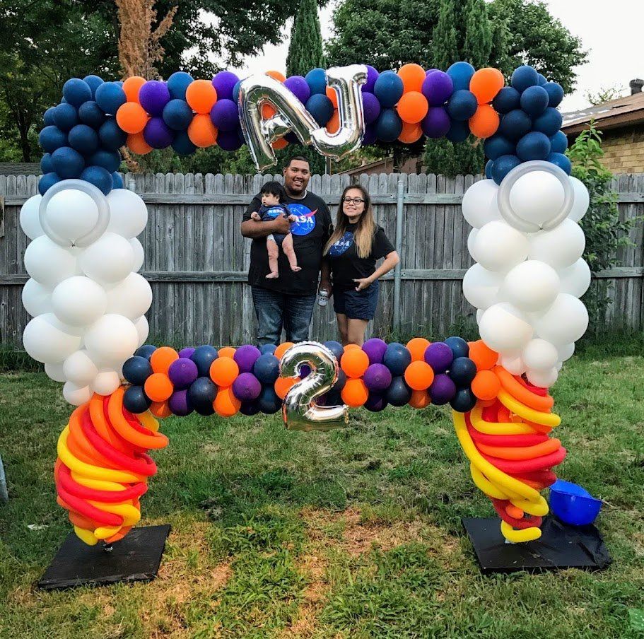 A family standing under a balloon arch with the number 2 on it