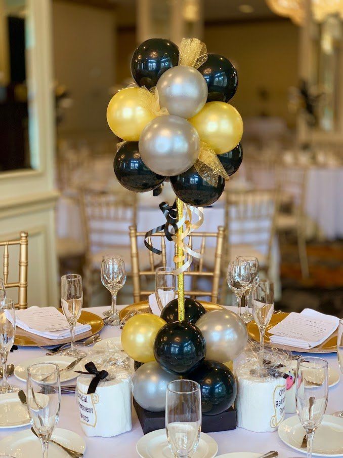 A table with plates , glasses , and balloons on it.