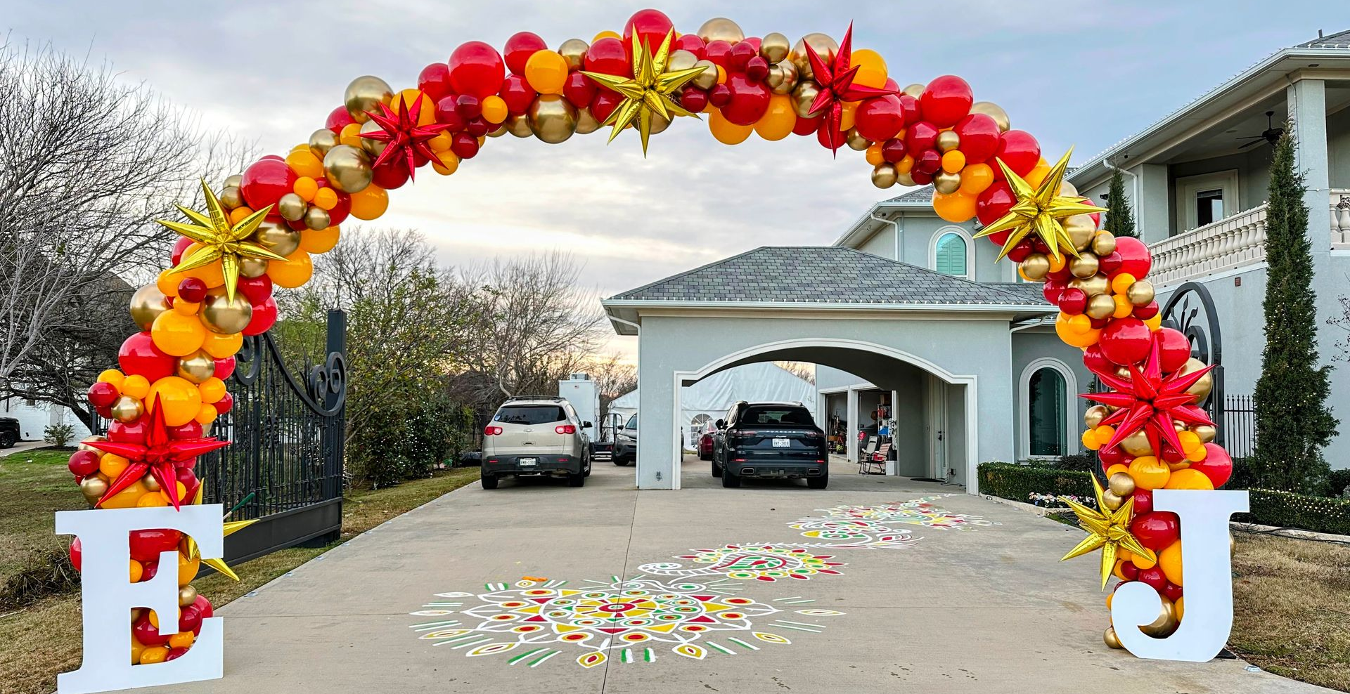 a detail balloon arch with red, gold, and orange balloons with extra foil balloons.