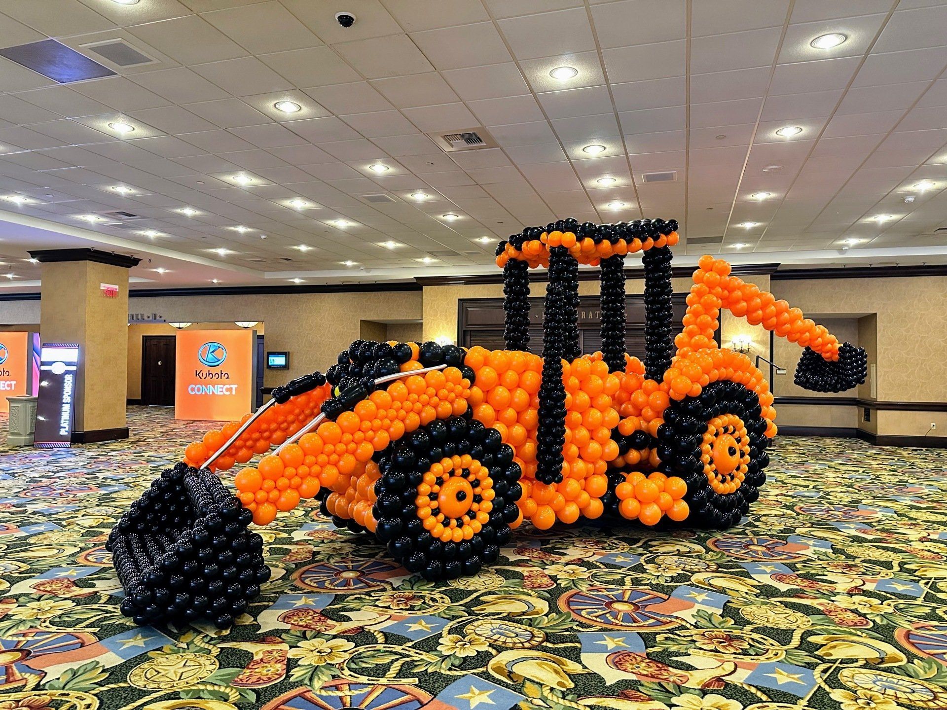 A bulldozer made out of balloons in a room.