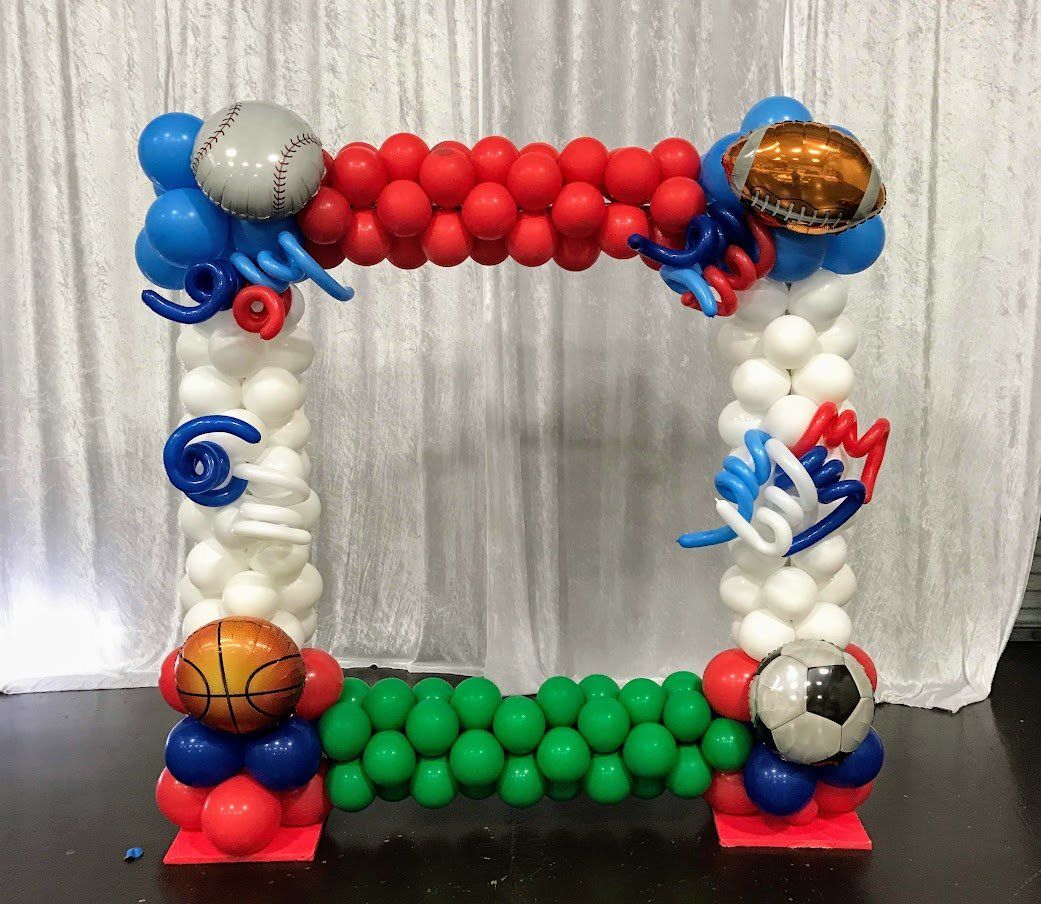 A picture frame made of balloons with a baseball , basketball , and soccer ball on it