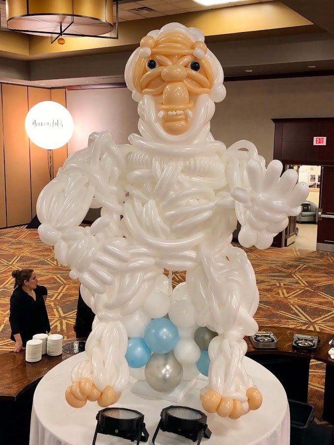 A statue made out of balloons is sitting on top of a table.