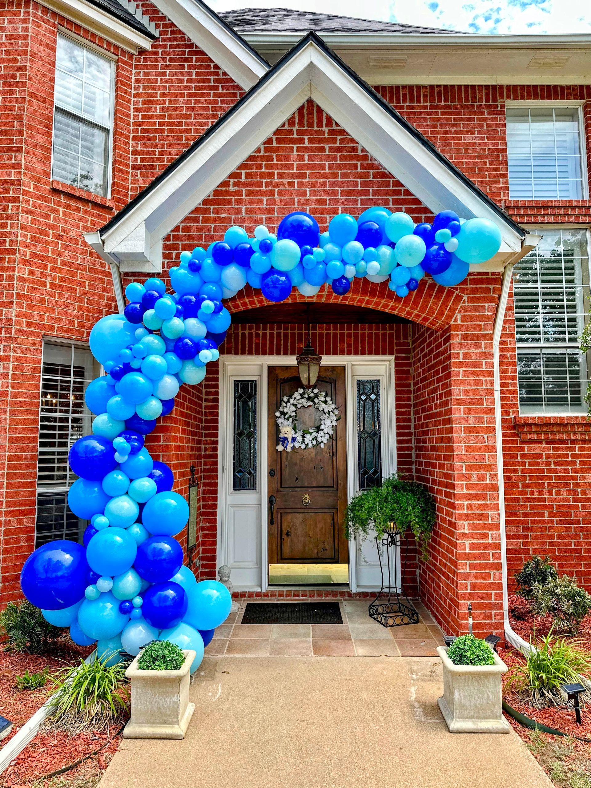 A brick house decorated with blue and white balloons for a baby shower.