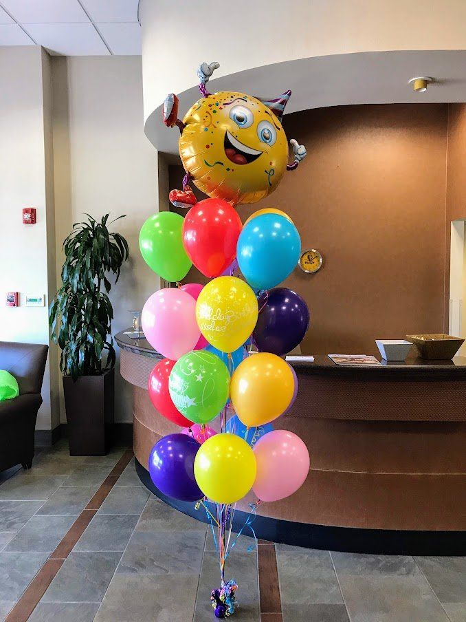 A bunch of colorful balloons are sitting on a table in a room.