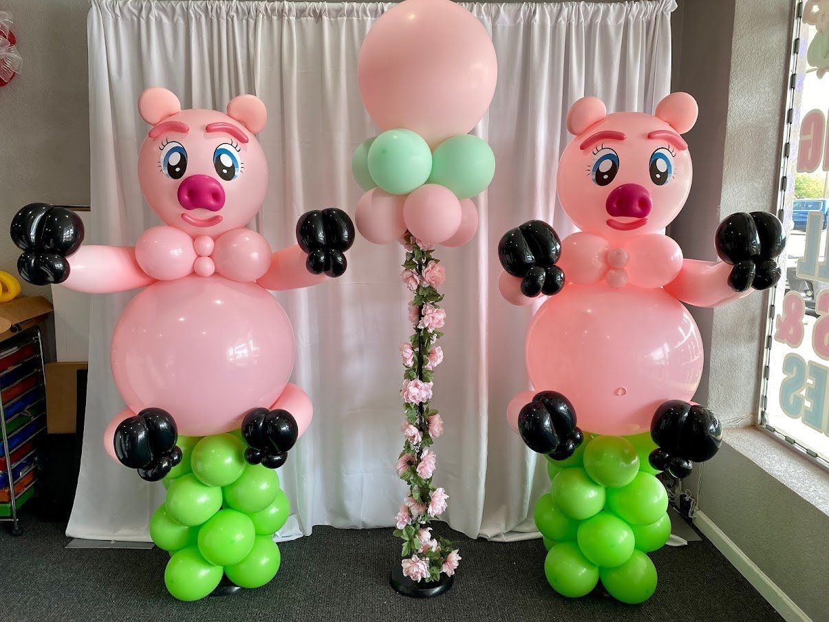 Three pigs made out of balloons are standing next to each other in a room.