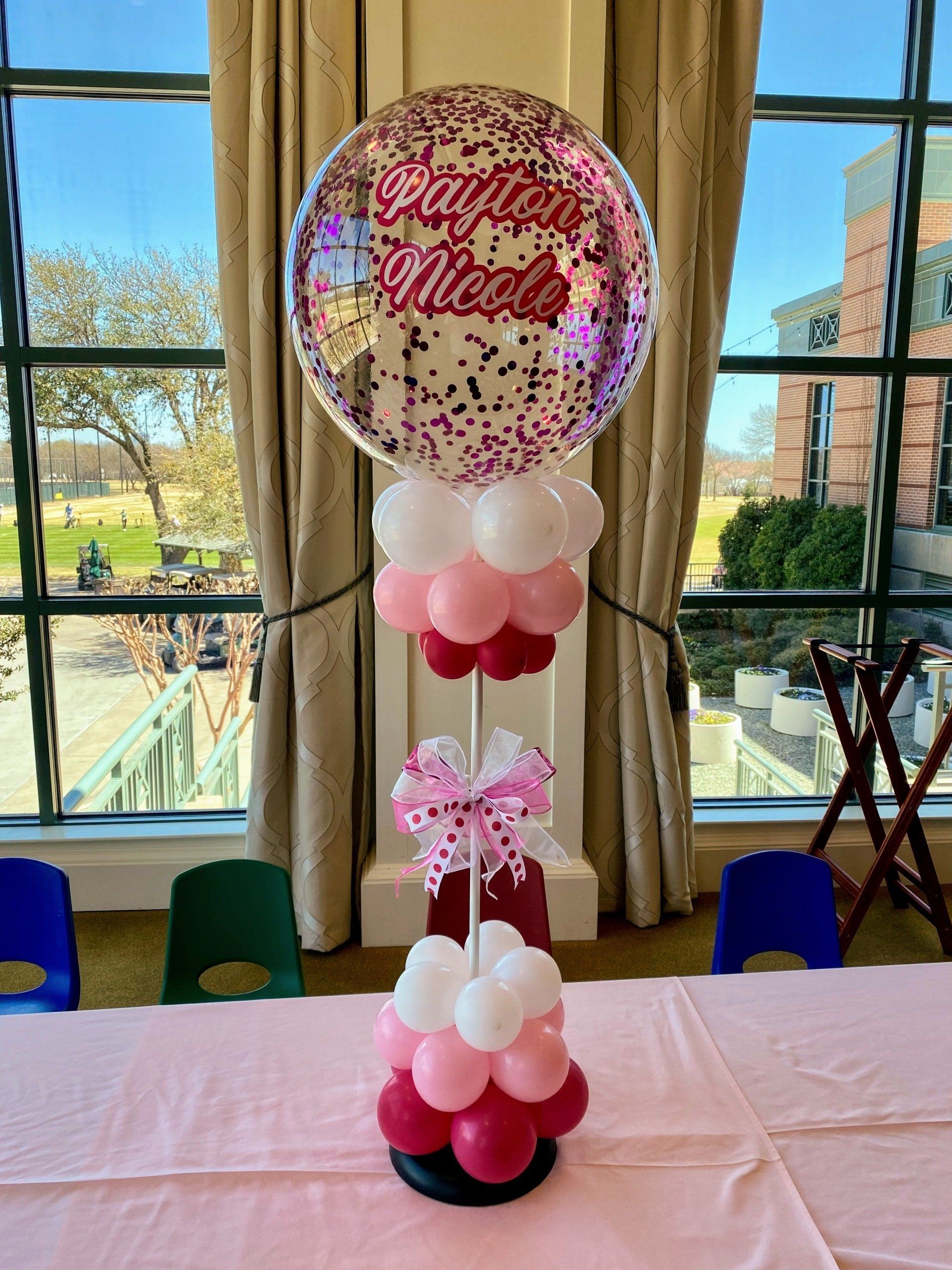 A table topped with balloons and a balloon with the name nicole on it.