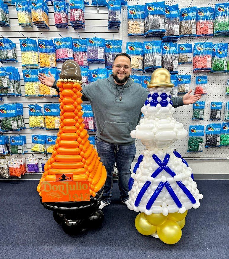 A man is standing next to two balloon sculptures in a store.