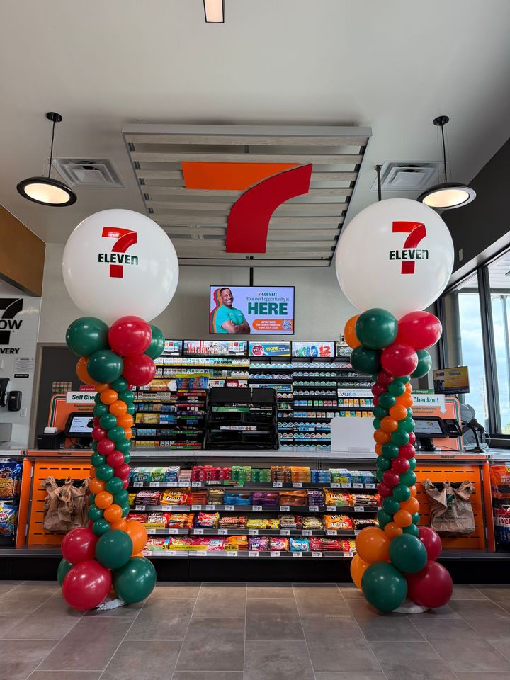 Branded balloon columns for a 7-Eleven grand opening in Fort Worth, featuring custom company colors and logo balloon toppers.