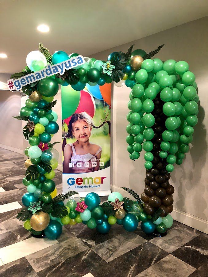 A green balloon arch with a palm tree in the middle