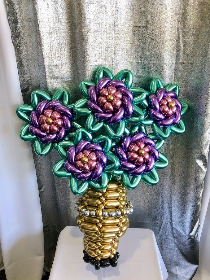 A vase filled with flowers made of balloons is sitting on a table.