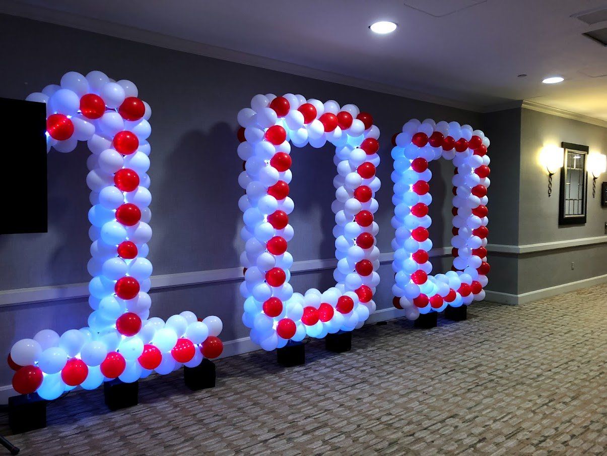 The number 100 is made out of red and white balloons