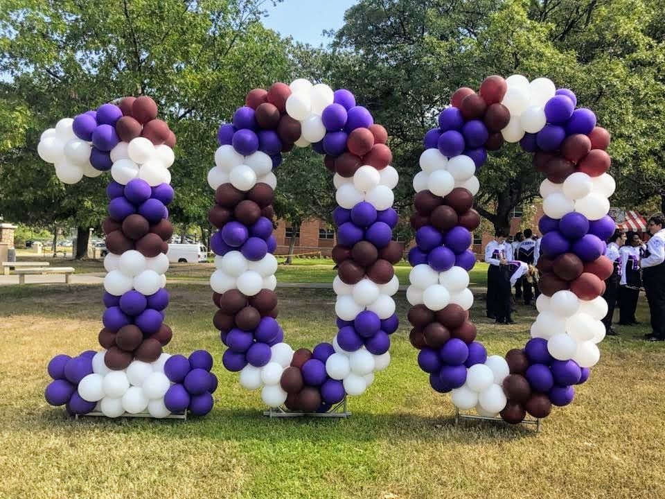 A large number 100 made of balloons in a field