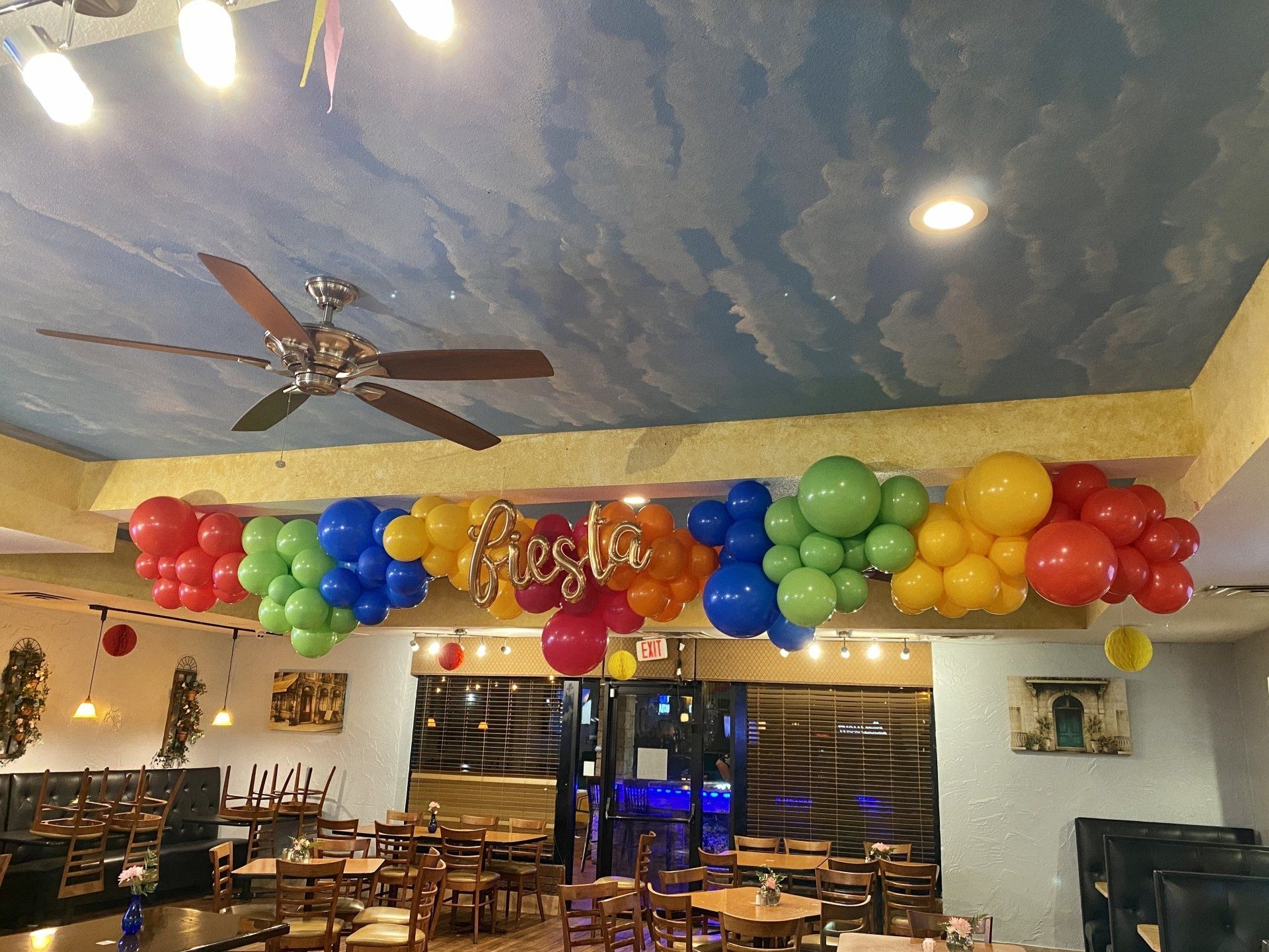 A restaurant is decorated with balloons and a ceiling fan.