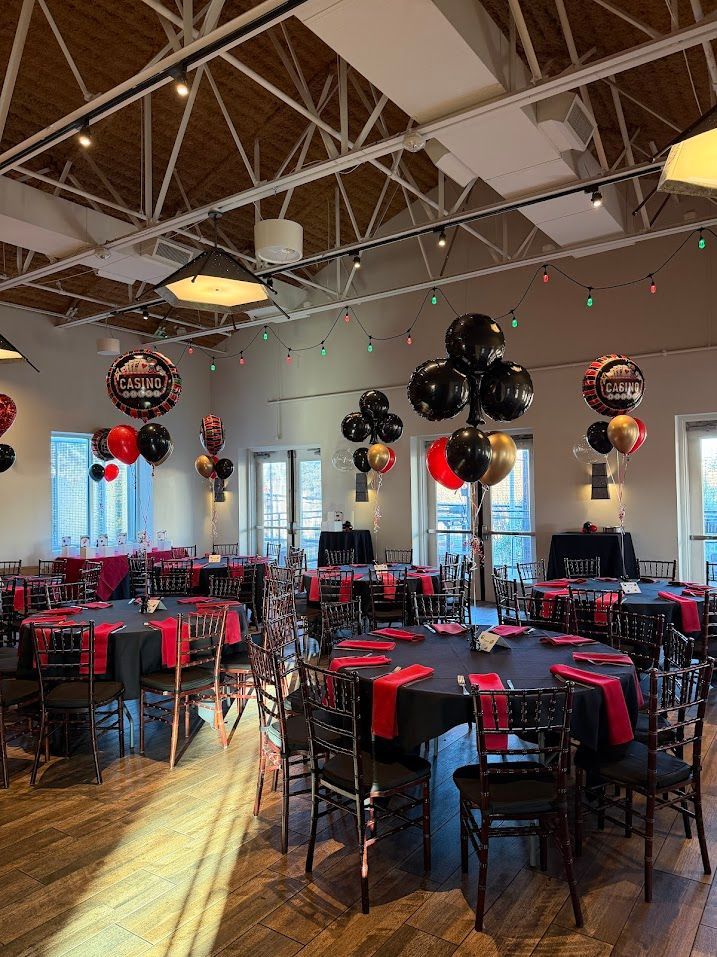 Corporate party balloon decor inside event venue with table styling and ceiling balloon accents