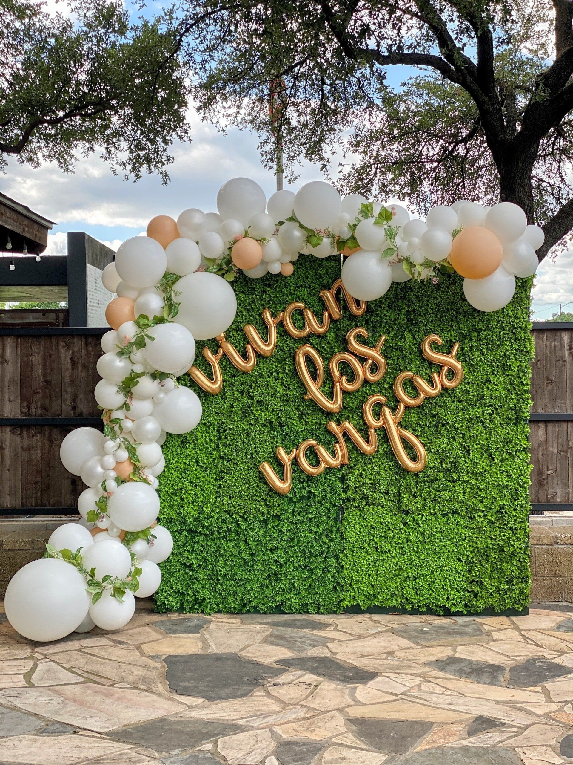 A green wall with balloons and a sign that says vivir las vegas