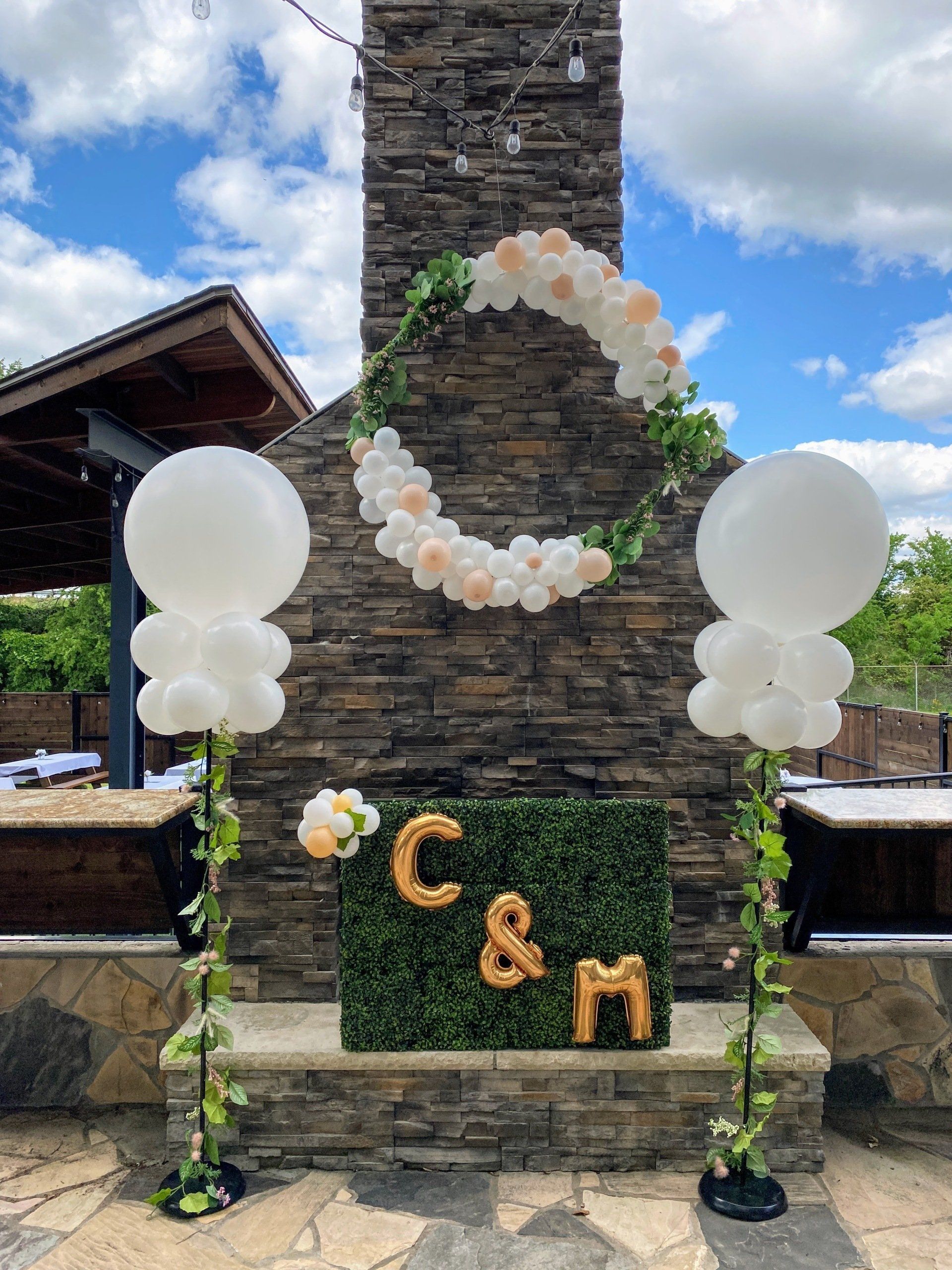 A fireplace decorated with balloons and a sign with the initials of the bride and groom.