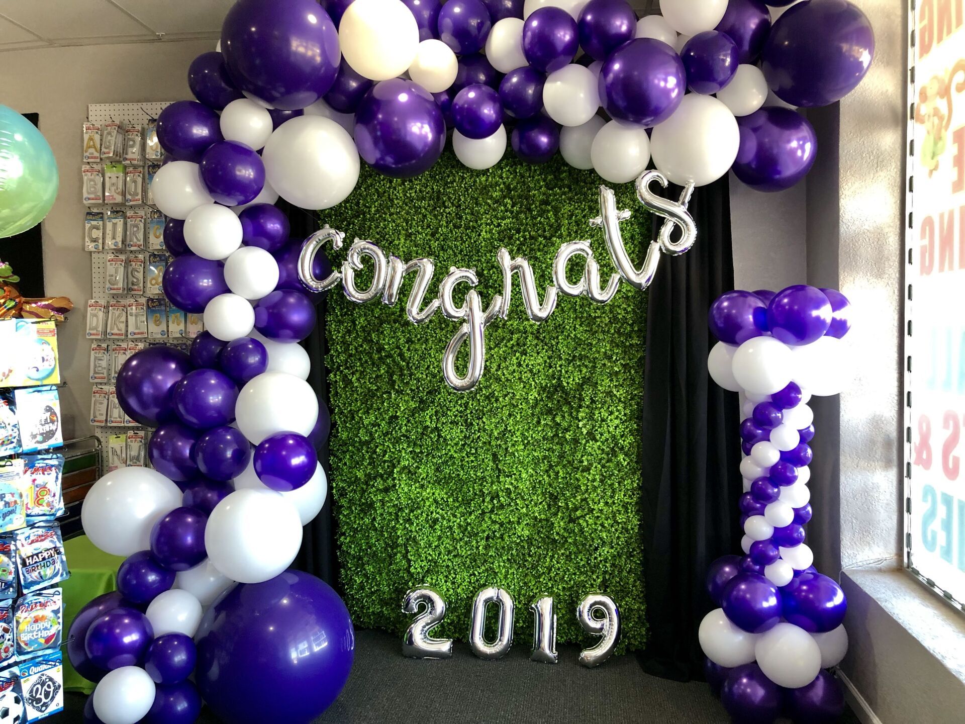 A room filled with purple and white balloons and a congratulations sign.