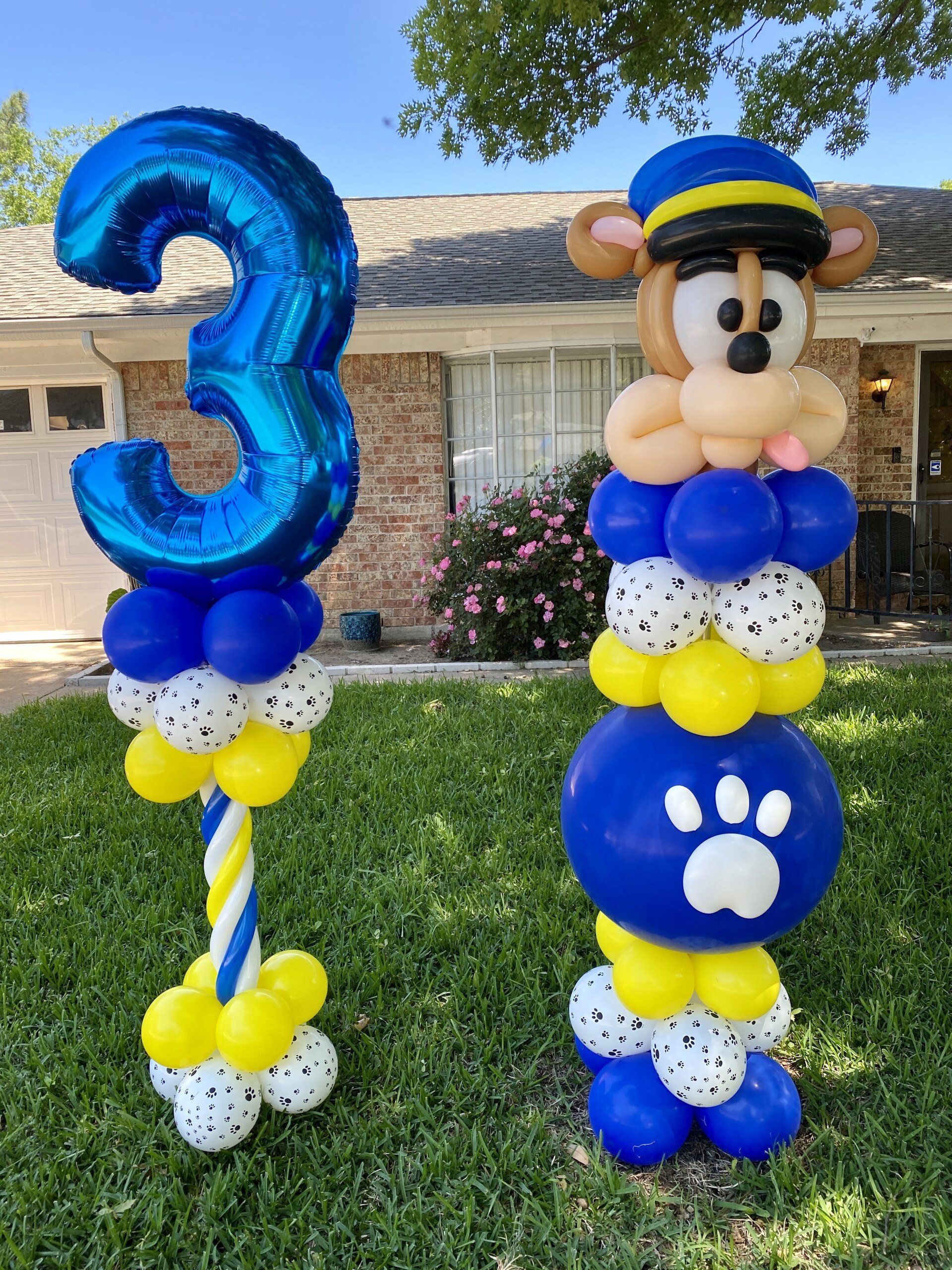 Balloons are stacked on top of each other in front of a house.