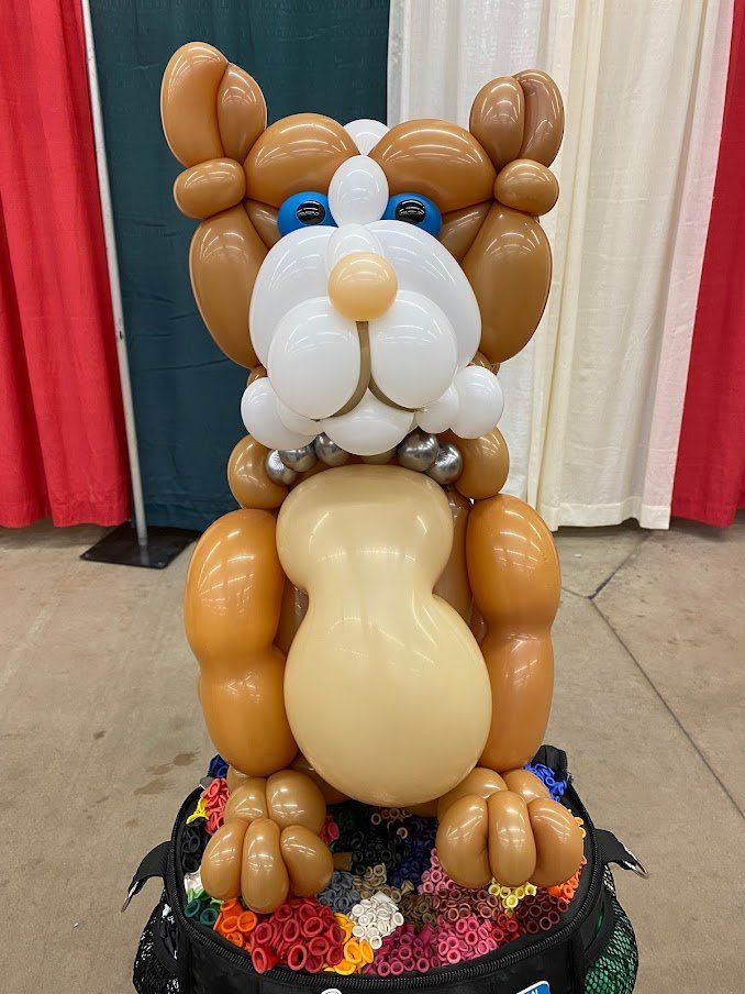 A bulldog made out of balloons is sitting on a table.