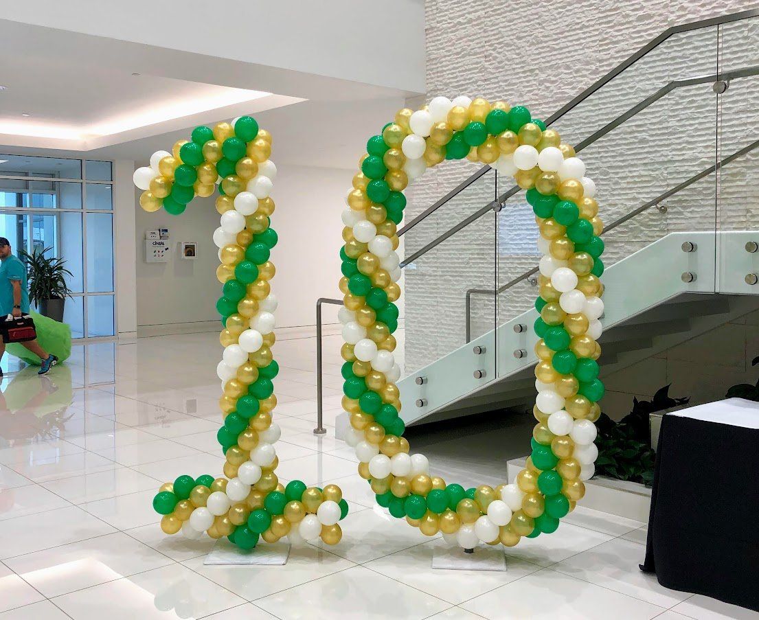 The number 20 is made of green , white and gold balloons.