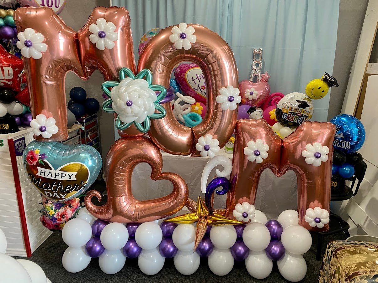 A bunch of balloons shaped like the word mom are sitting on a table.