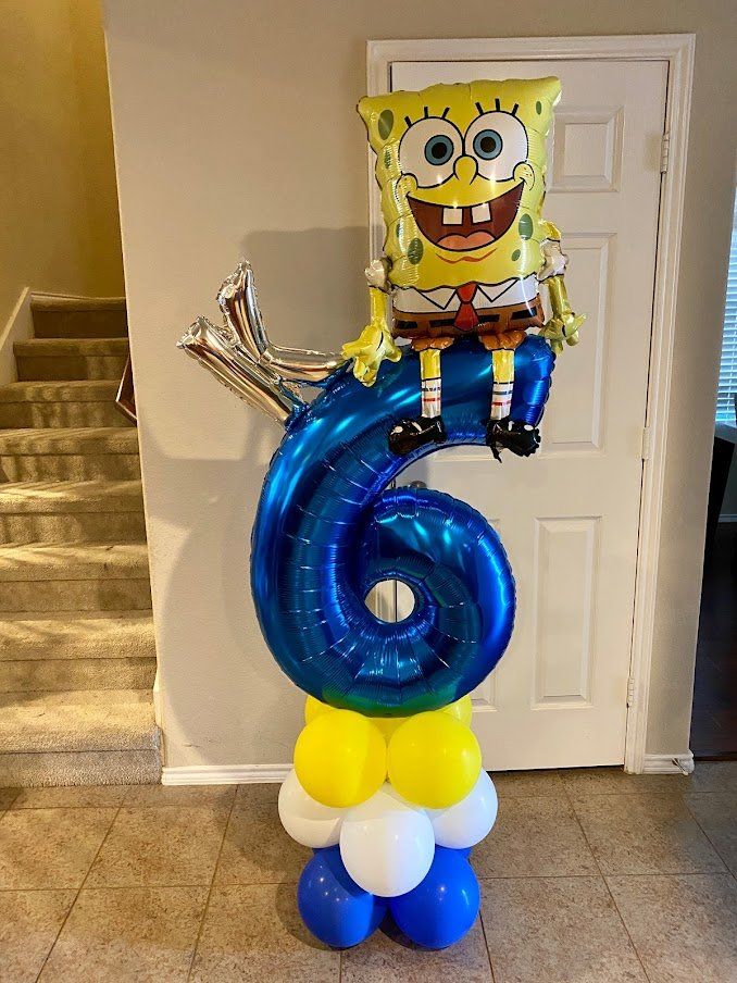 A spongebob balloon is sitting on top of a number six balloon.