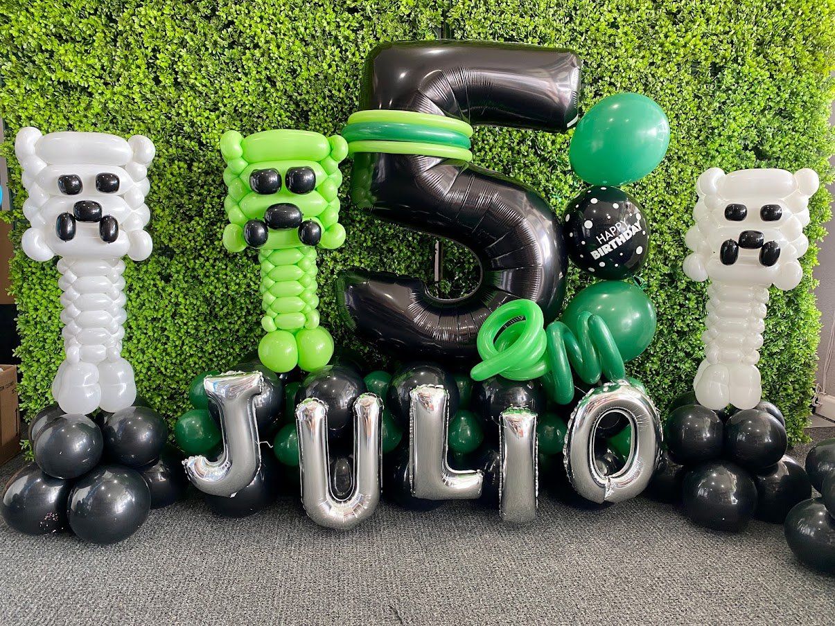 A bunch of balloons are sitting in front of a green wall.