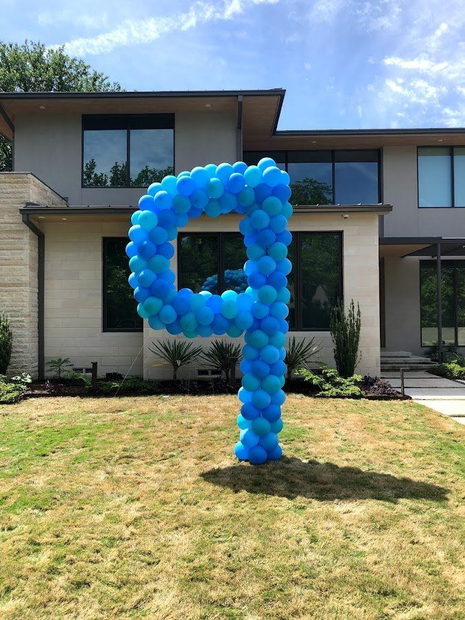 A letter p made out of blue balloons in front of a house