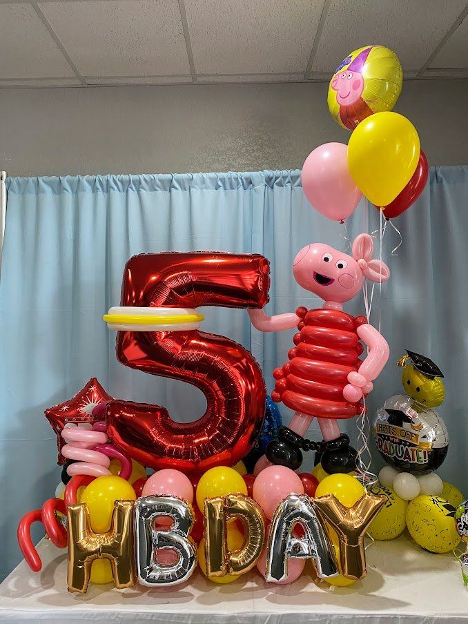 A table topped with balloons and a pig made out of balloons.