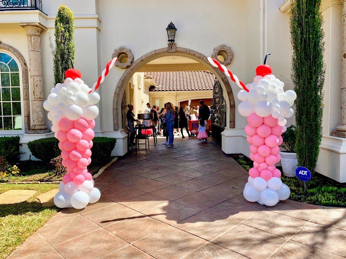 A group of people are standing in front of a building with balloons in the shape of milkshakes.