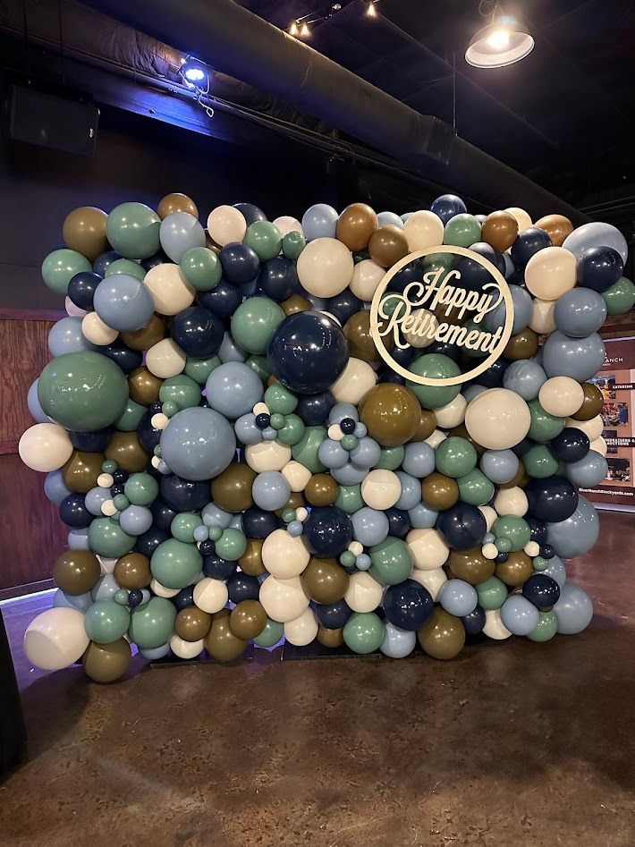 A wall of balloons with a sign that says `` happy retirement ''.