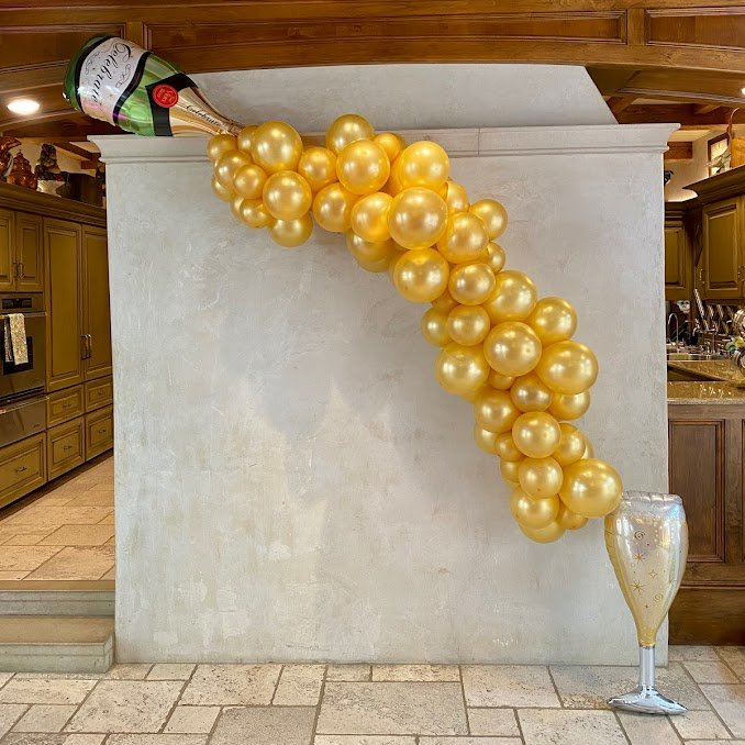 A bottle of champagne and a glass of champagne are made out of balloons.
