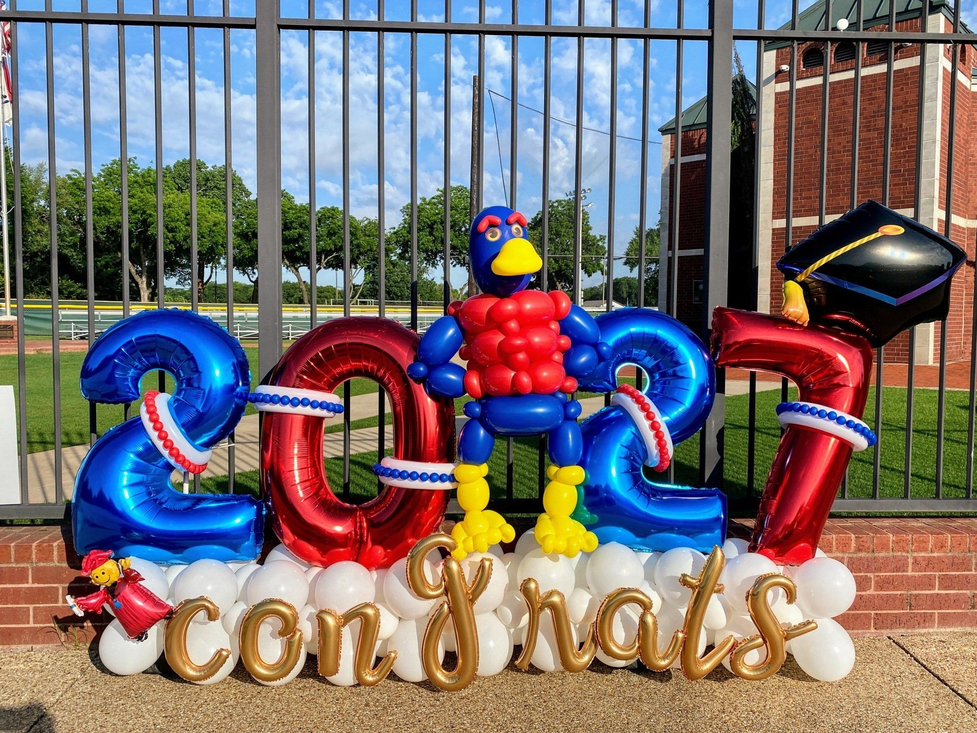 A bunch of balloons are sitting on top of each other in front of a fence.