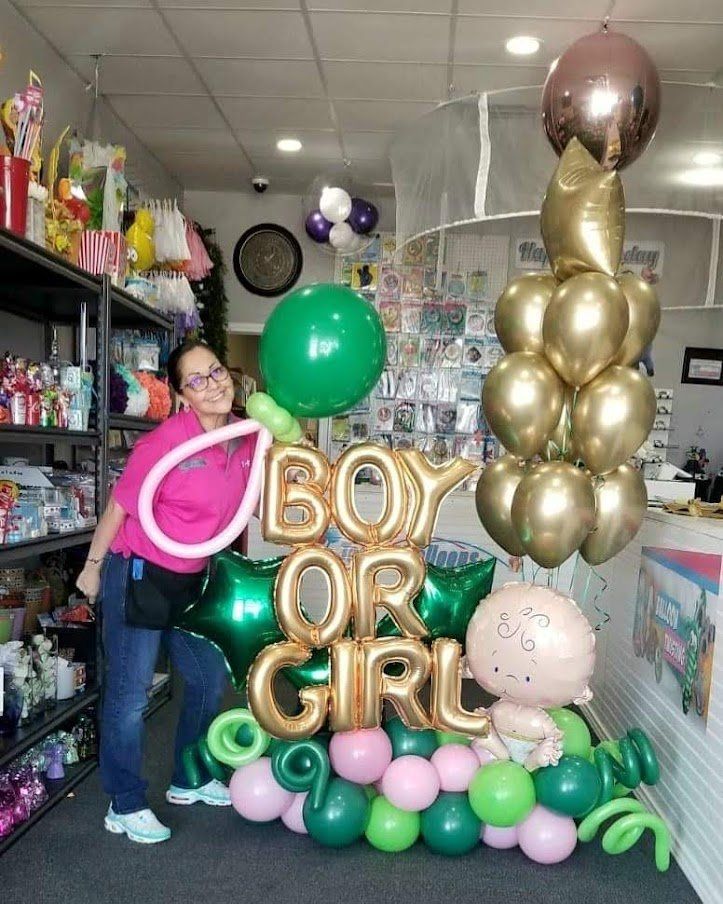 A woman is standing in front of a bouquet of balloons that says boy or girl.