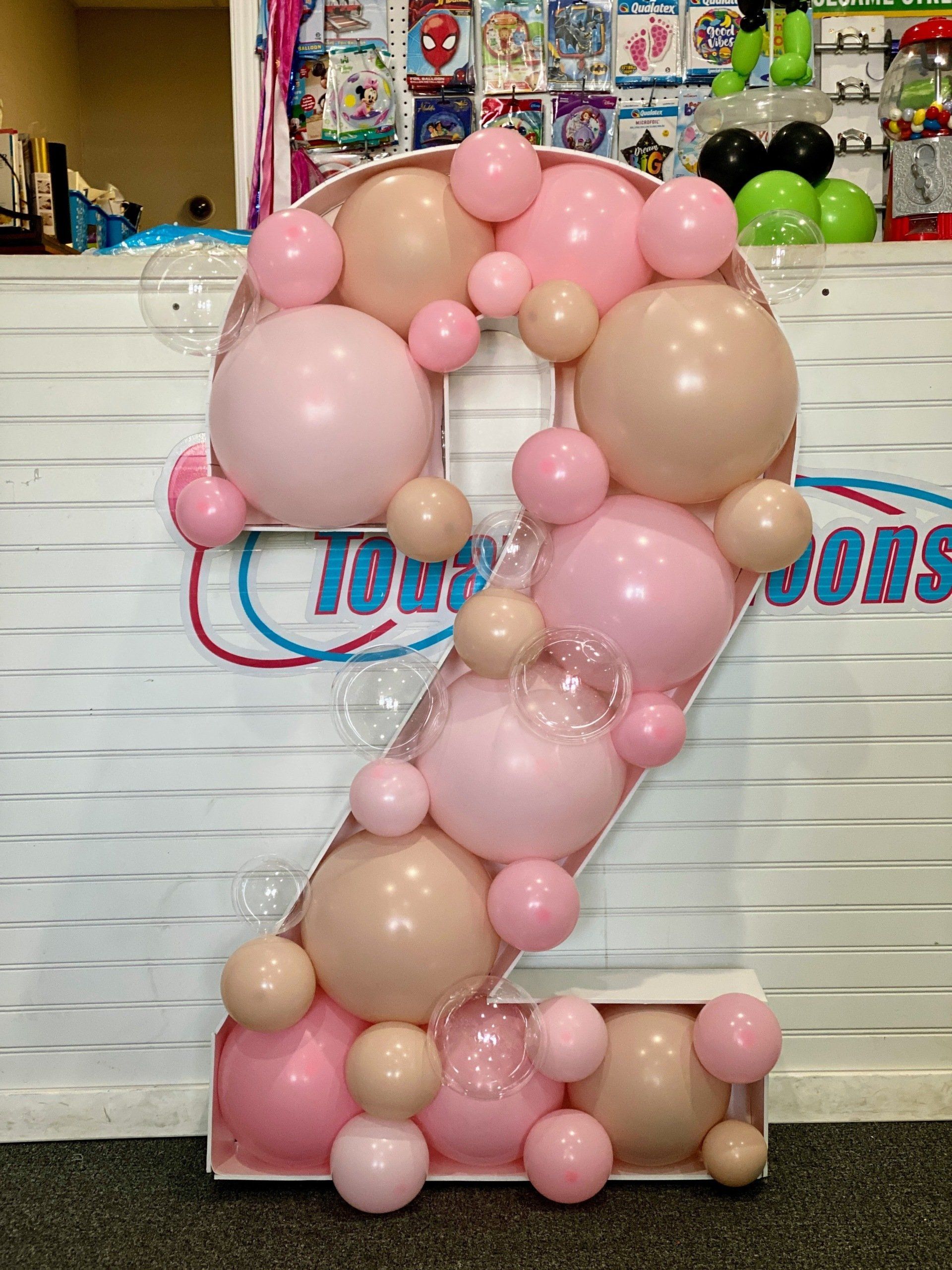 The number 2 is made of pink and tan balloons.