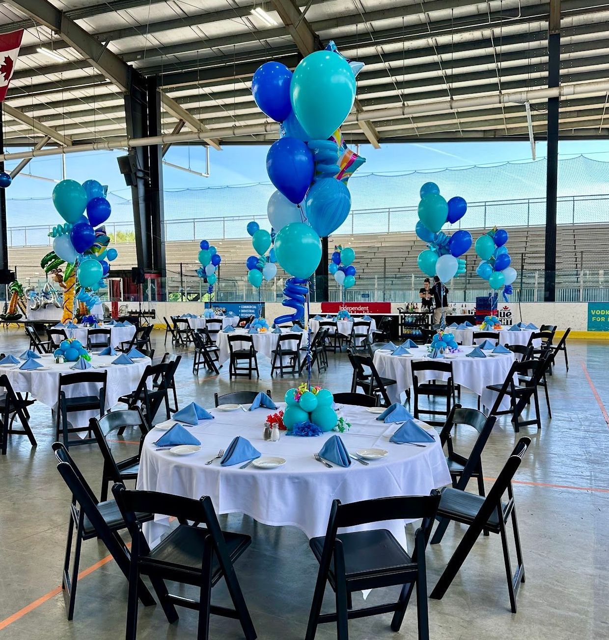 A large room filled with tables and chairs decorated with blue balloons.