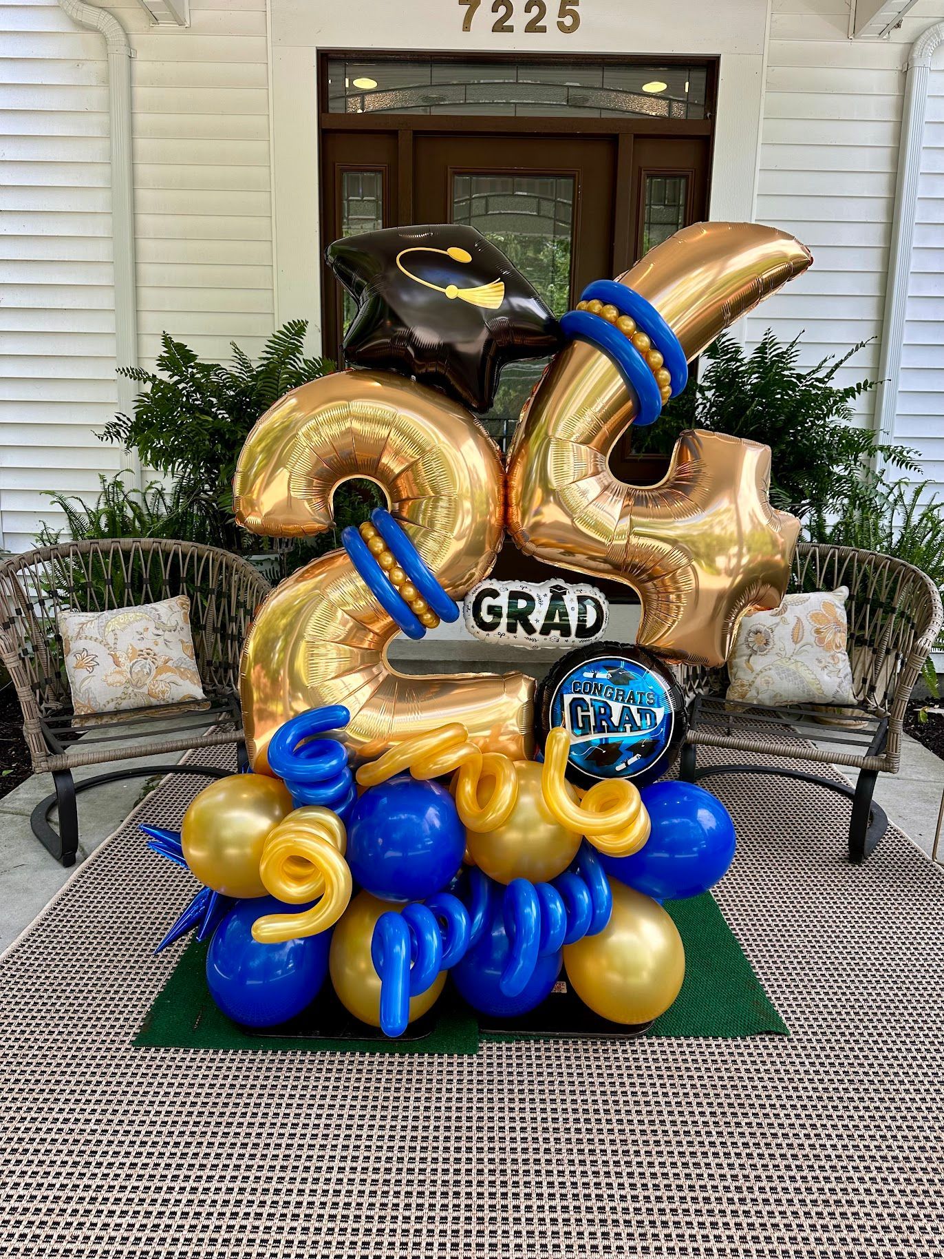 A bouquet of blue and gold balloons with a graduation cap on top of them.