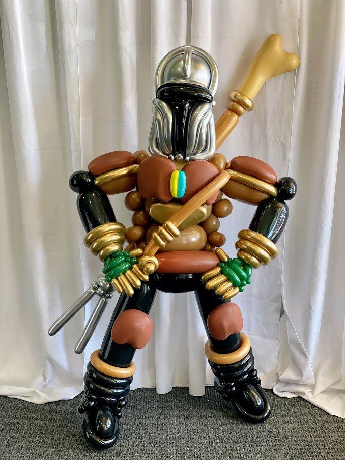 A man made out of balloons is standing in front of a white curtain.