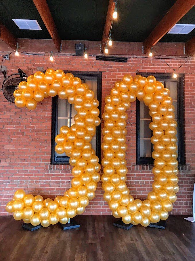 A large number 30 made out of balloons in front of a brick wall.