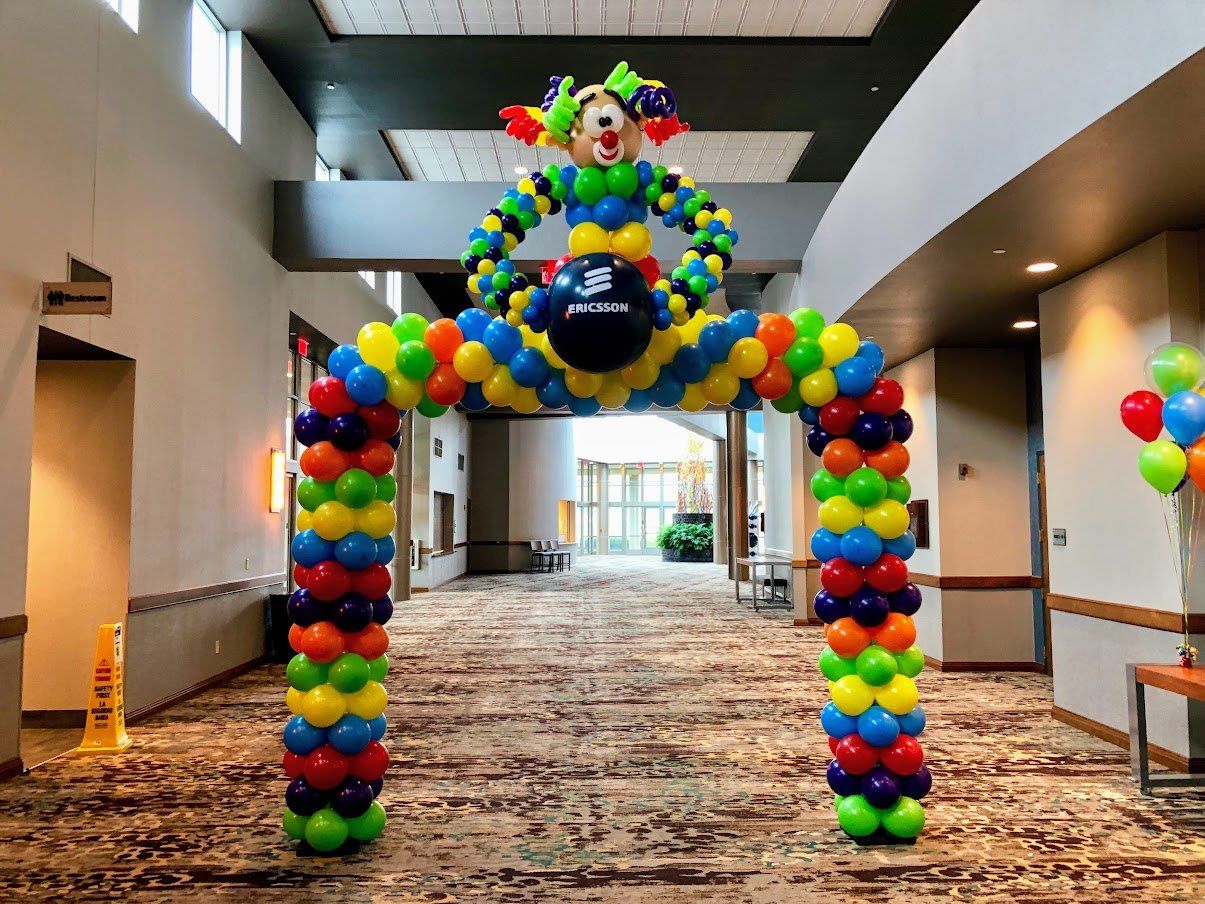 A balloon arch with a clown on top of it