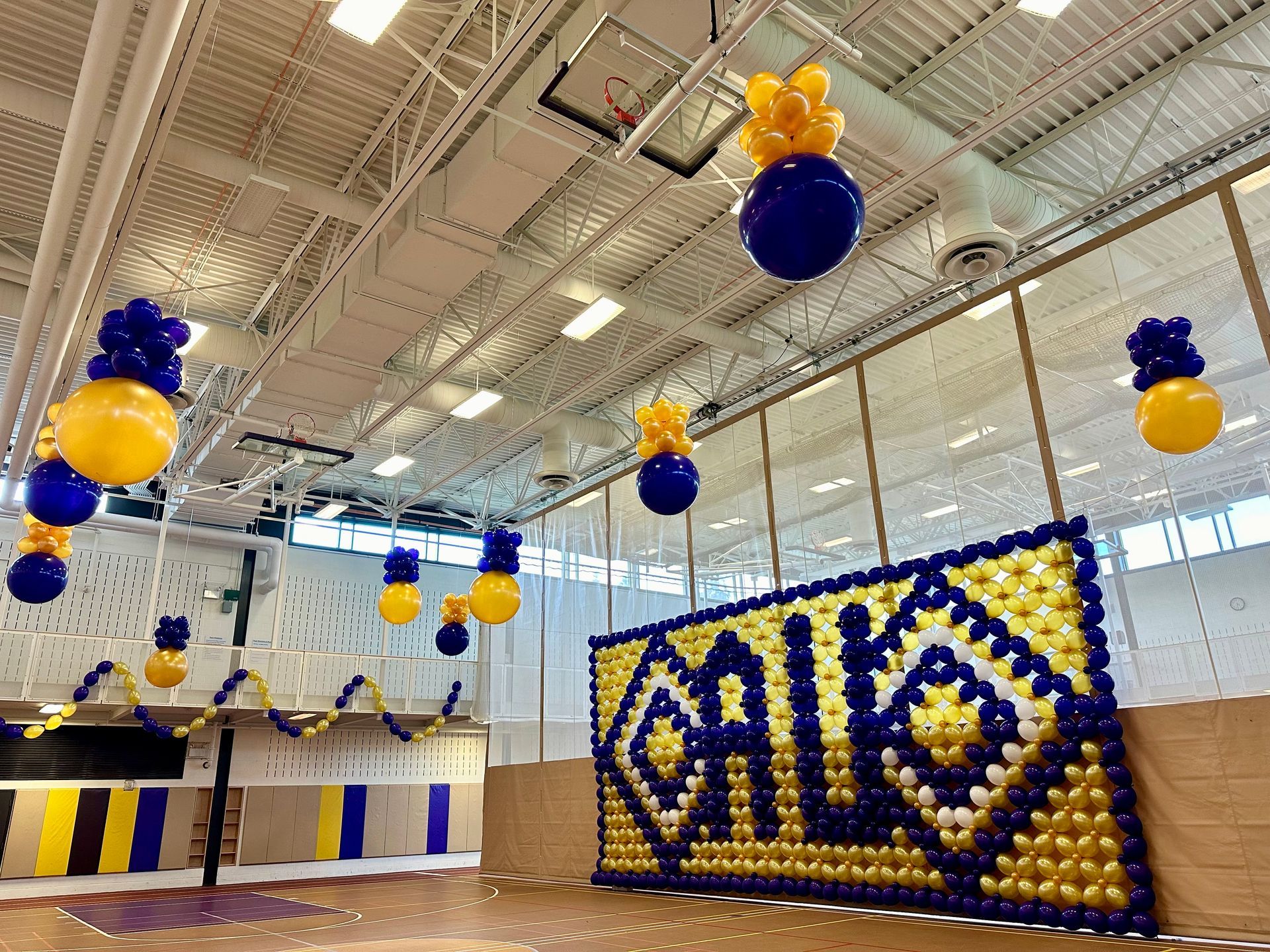 Ceiling balloon decor installation with hanging balloons for corporate event inside large indoor venue