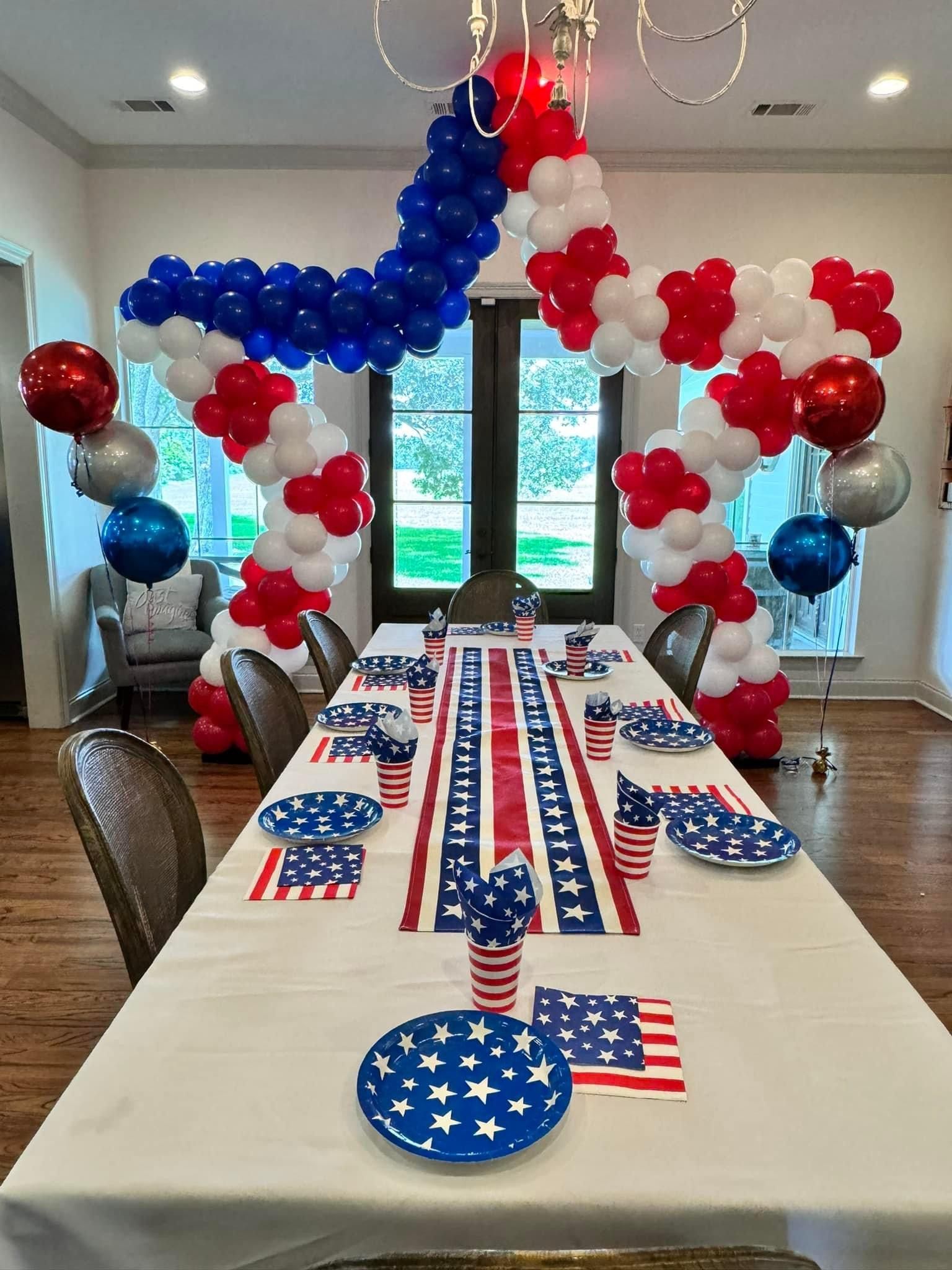 A table is decorated with red , white and blue balloons for a fourth of july party.