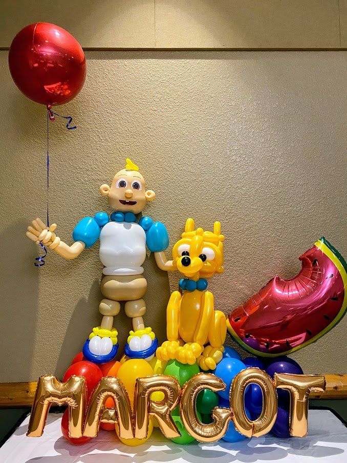 A baby and a dog made out of balloons with the name marcot written in gold letters.