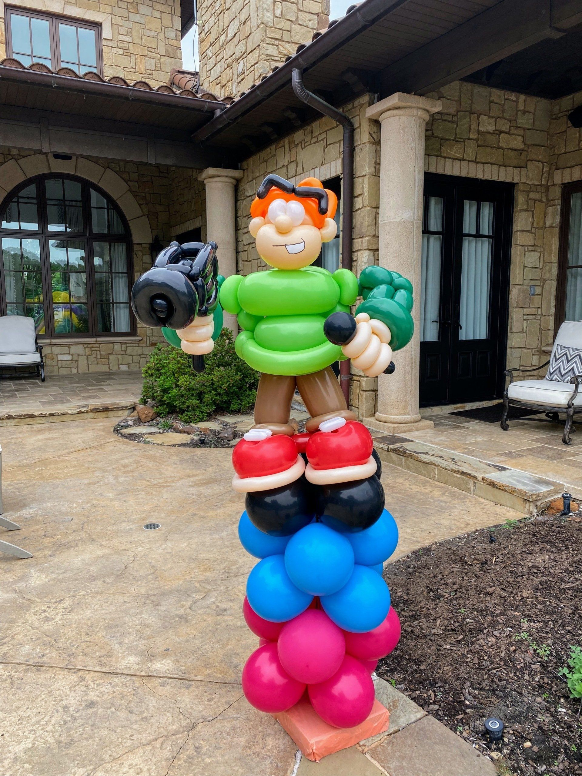A balloon sculpture of a boy standing on top of a stack of balloons.