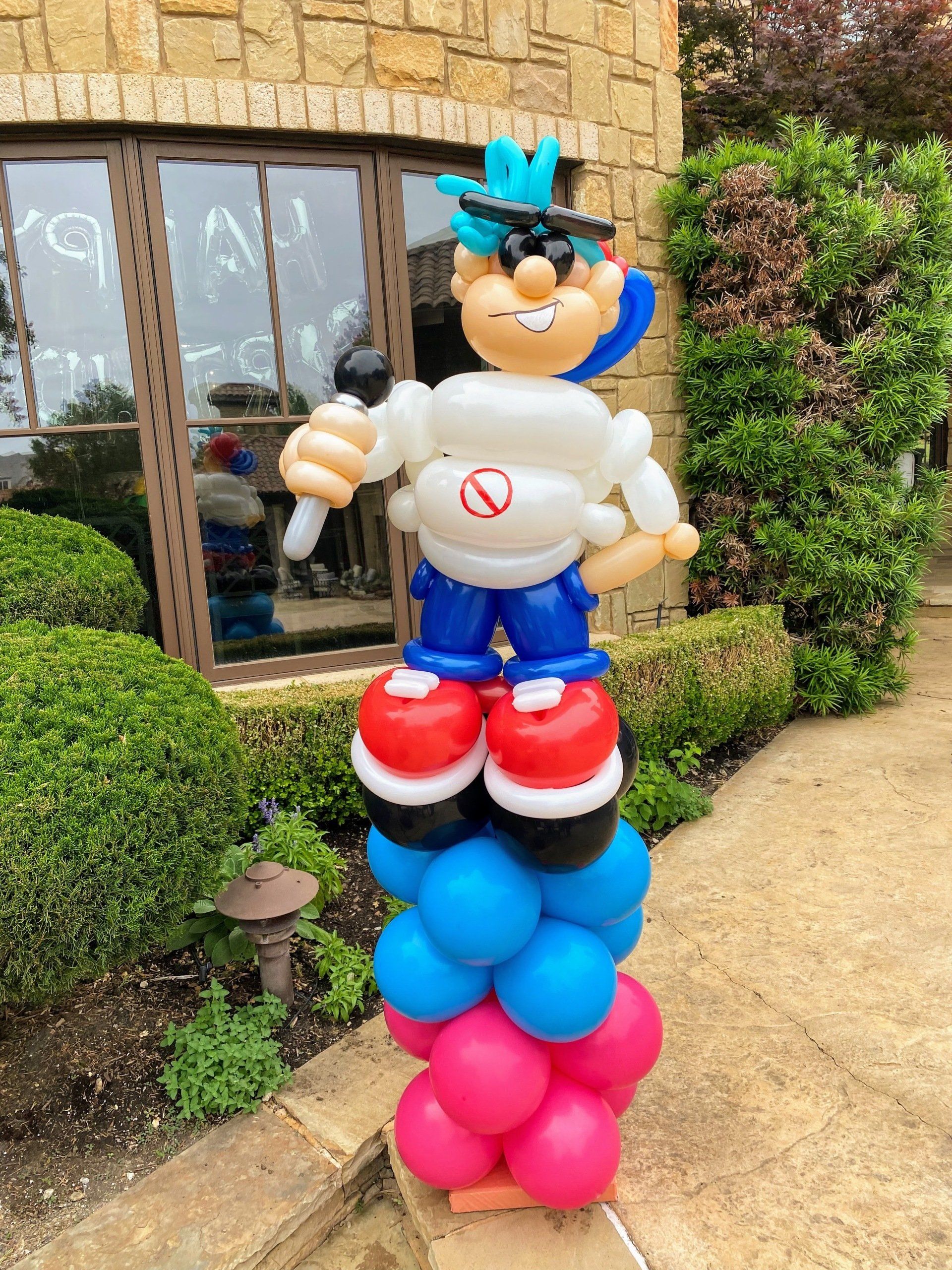 A man made out of balloons is standing on top of a stack of balloons.