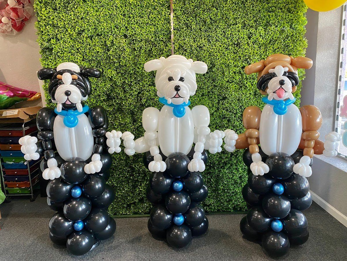 Three dogs made out of balloons are standing next to each other.