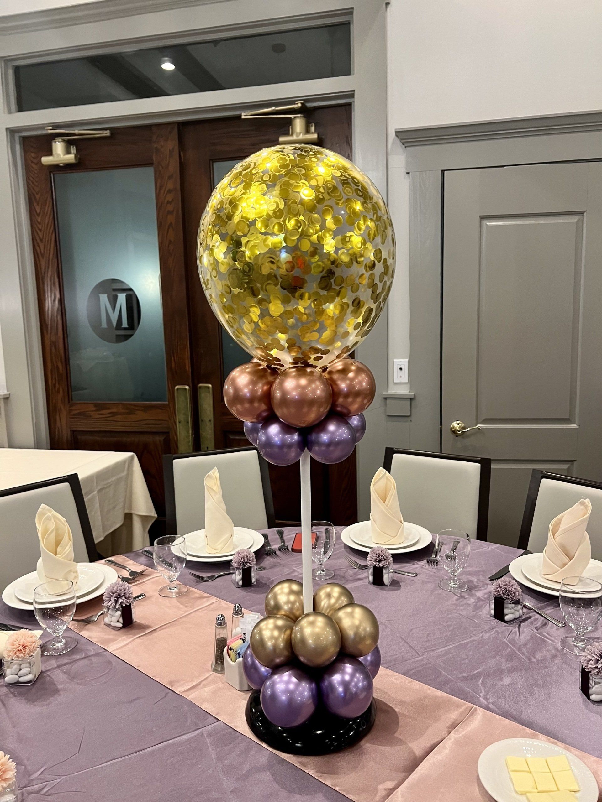 A table with plates , napkins , and balloons on it.