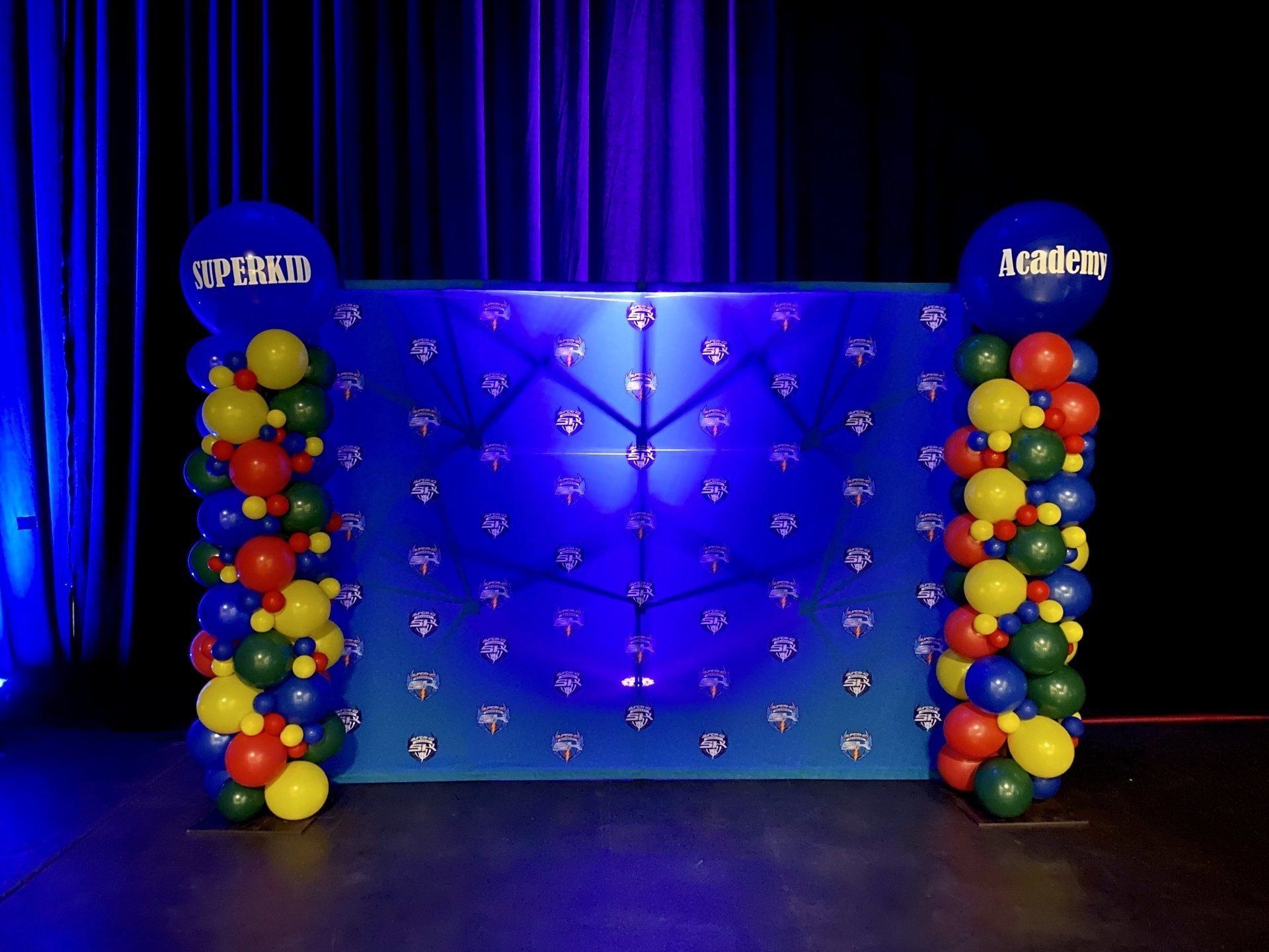 A blue wall with balloons and a clock on it