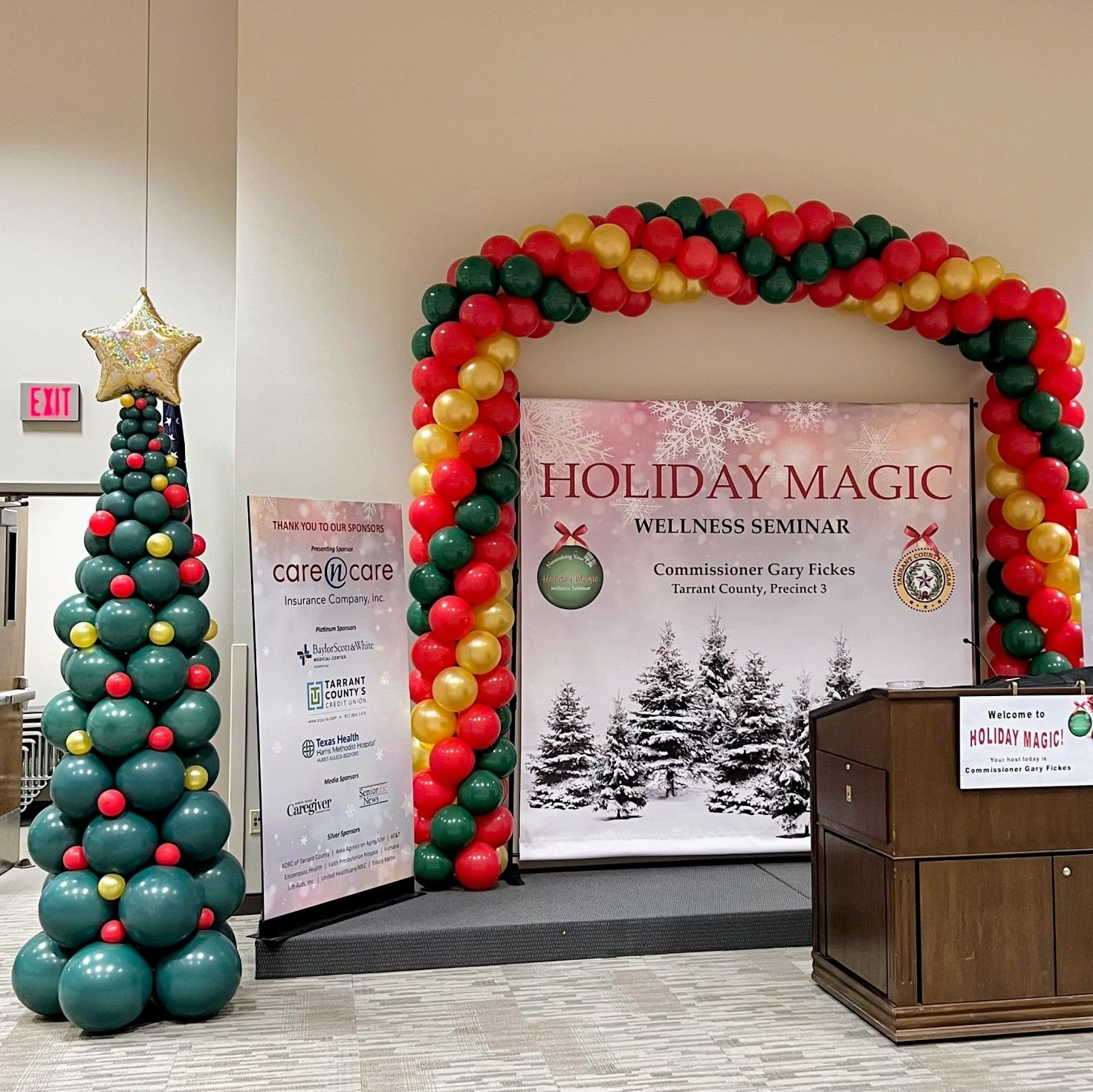 A christmas tree made of balloons in front of a sign that says holiday magic